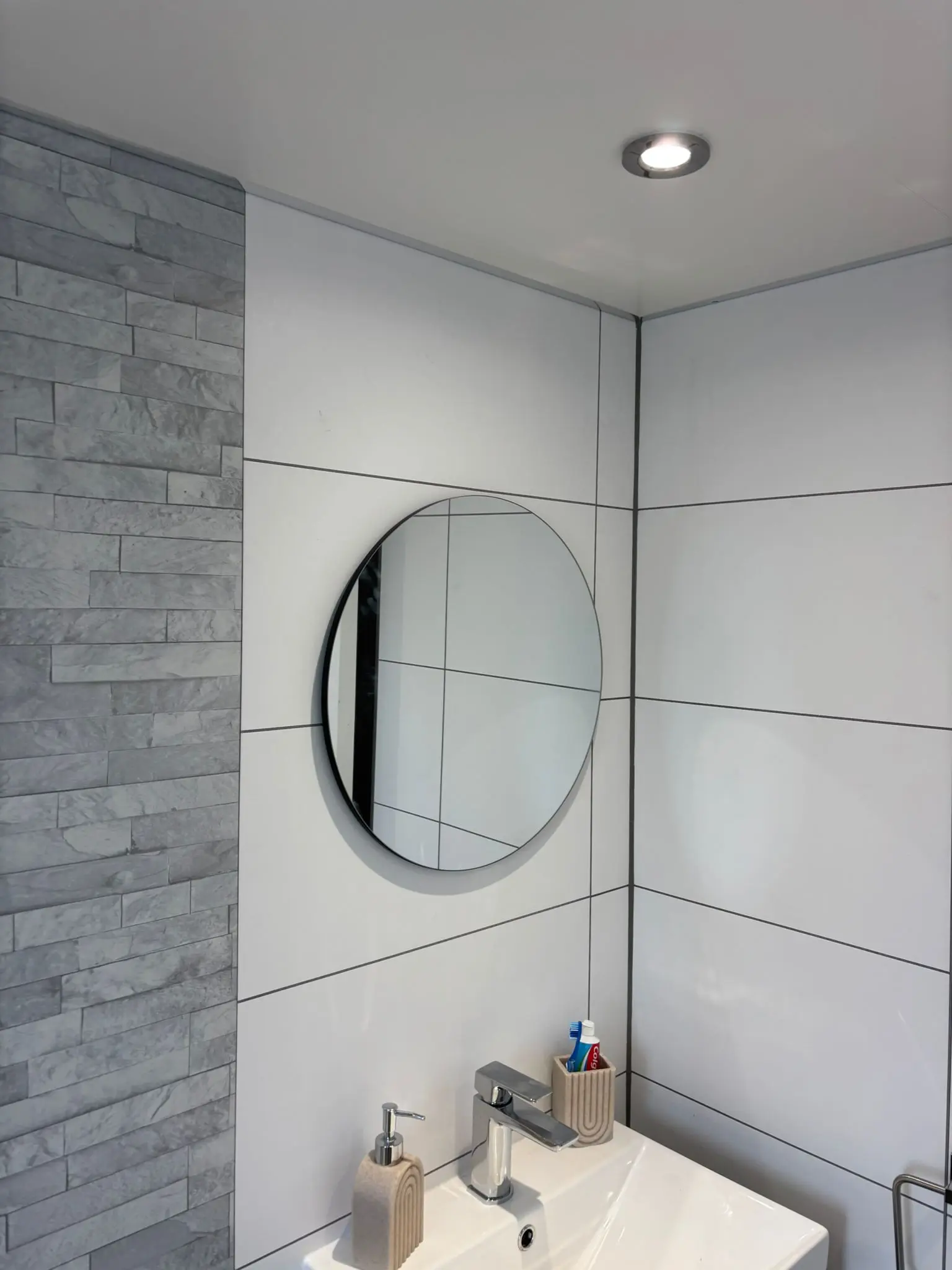 Round black-framed mirror above vanity with recessed LED spotlights in Stockbridge bathroom