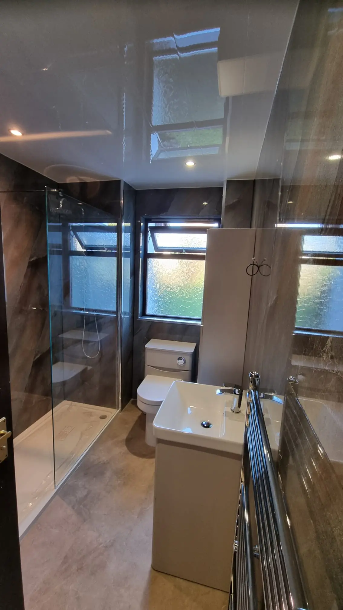 Dark wet wall bathroom with glass shower enclosure